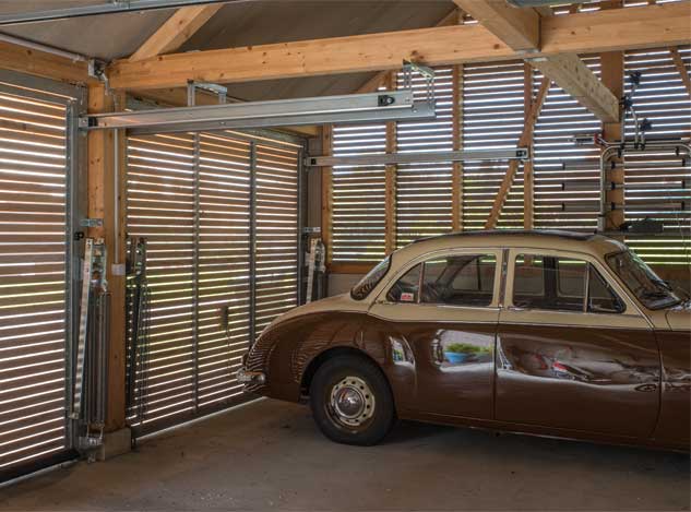 **Die Garage des neuen Taunerhauses Hörhausen** Die garage des Taunerhauses Hörhausen bietet auch Platz für einen Oldtimer, einen 1958 MG Magnette ZB. Die Lärchenholzverschalung mit im Querschnitt quadratischen Holzlatten schliessen die offenen Aussenhaut der garage und bilden einen licht- und luftdurchlässigen Innenraum.