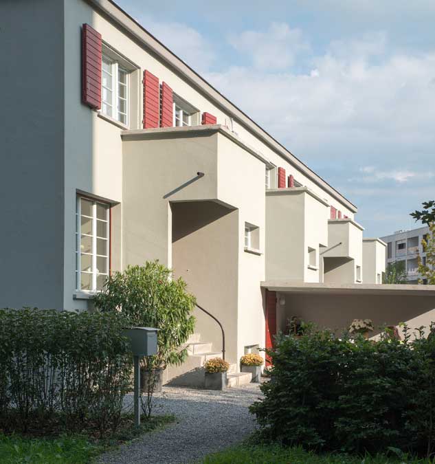 Meilihaus, Feldbreite Emmenbrücke Luzern.  Stoffel Schneider Architekten AG.   Der Vorbau für den Eingang und die Toilette gliedert die Fassade und das Gesamtvolumen. Die Fensterteilung mit den schlanken Glassprossen sind den Originalfenstern abgenommen und nachgebaut. Die dunkelroten Klappläden sind die Originalläden und  konnten saniert und aufgefrischt werden.