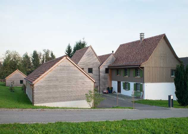 **Der Zugangshof des Taunerhauses Hörhausen** Die Garage und der Anbau mit seinen klar lesbareb zwei Gibeln bilden mit dem Altbau einen keinen Zugangshof. Er dient als Ankunftshof, Garagenvorplatz und Spielhof. Von ihme aus wird über den alten Haupteingan im Altbau das gebäude erschlossen und betreten. Der Bodenbelag ist der Nutzung geschuldet in Asphalt, wogegen den Vorplatz vor dem Altbau als Katzenkopfpflaster angelegt ist.