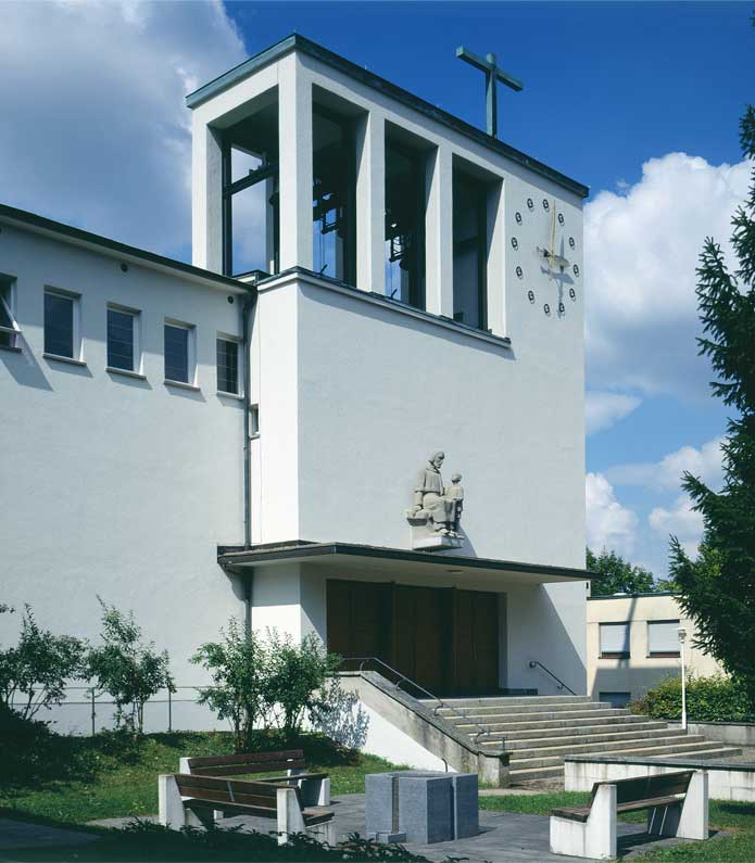 **Aussenansicht mit Glockenturm ** Der Haupteingang der katholischen Kirche St. Theresia in Zürich Friesenberg wird über eine breite Freitreppe erreicht und liegt im eigentlichen Glockenturm. Die Kirche wurde vom Architekten Fritz Metzger im Jahre 1933 erbaut und gilt als innovativer Bau der damaligen Zeit. Sie ist ein Vertreter des Modernen Bauens der Schweiz. 1947 ergänzte Richard Seewald die Wandbilder im Hauptschiff. In den siebziger Jahren gestaltete der Architekt Walter Moser die Kirche tiefgreifend um.